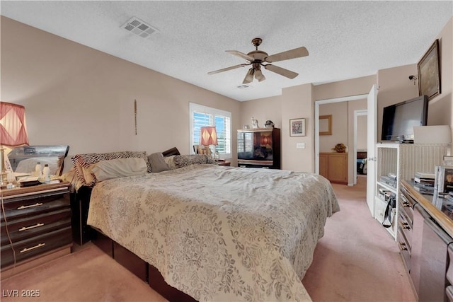 bedroom with light carpet, a ceiling fan, visible vents, and a textured ceiling