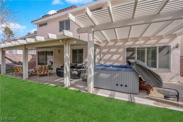 back of house with a hot tub, a lawn, a patio area, a pergola, and stucco siding