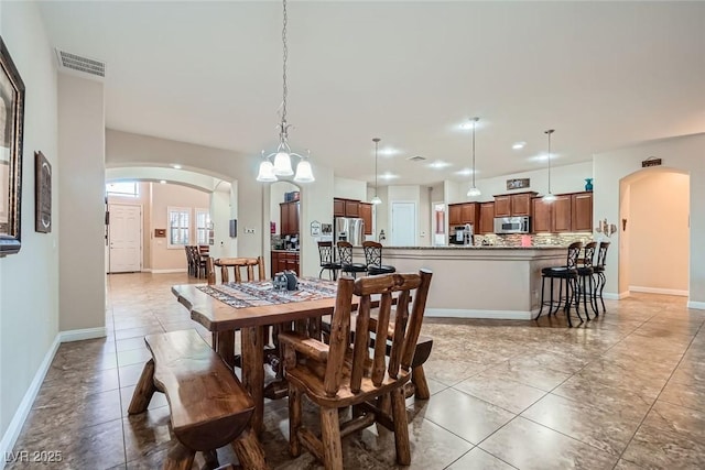 dining area featuring arched walkways, visible vents, baseboards, and light tile patterned flooring