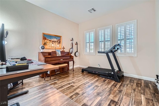 home office with baseboards, visible vents, and wood finished floors