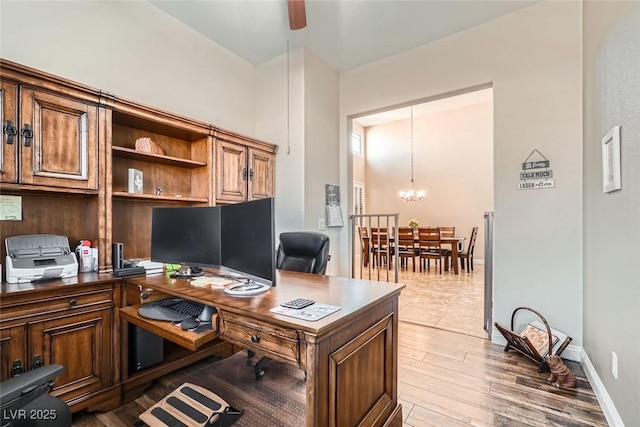 office featuring light wood-style flooring, baseboards, and ceiling fan with notable chandelier