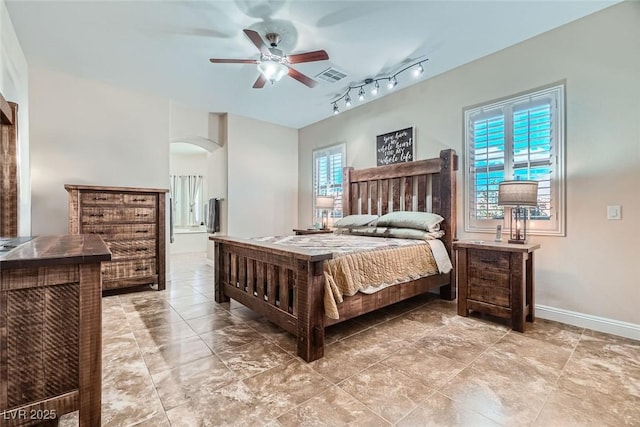 bedroom with arched walkways, multiple windows, visible vents, and baseboards