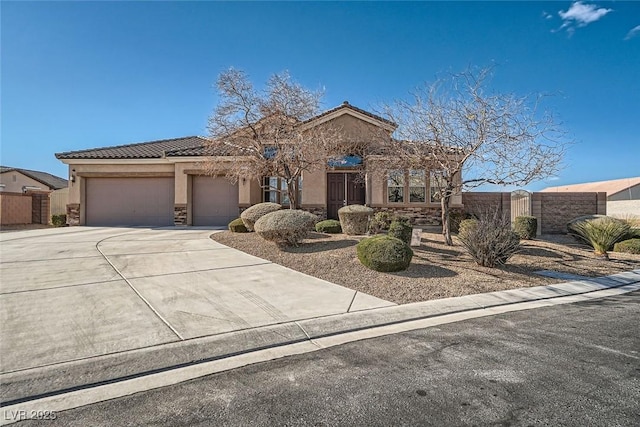 mediterranean / spanish house with a garage, a tile roof, concrete driveway, stone siding, and stucco siding