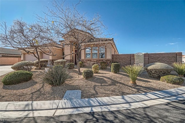 view of front of house featuring an attached garage, fence, stone siding, a gate, and stucco siding