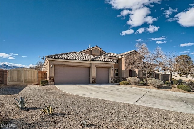 view of front of home featuring an attached garage, driveway, a tiled roof, a gate, and stucco siding