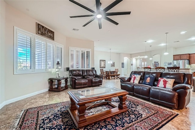 living room with ceiling fan, visible vents, and baseboards