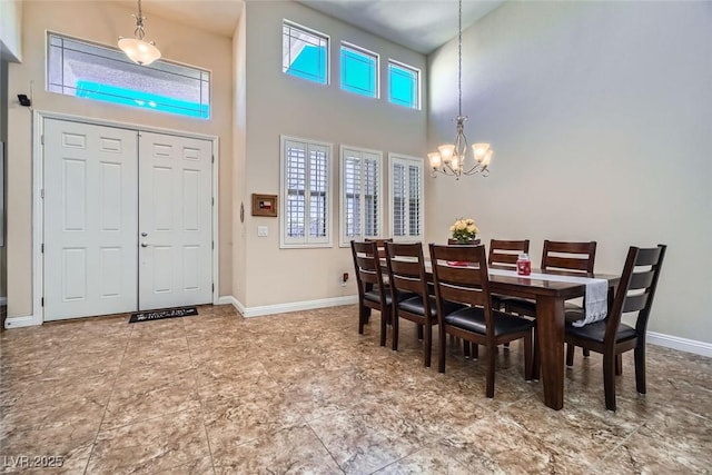 dining space featuring baseboards, a high ceiling, and a notable chandelier