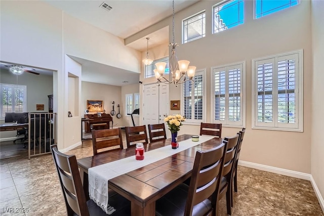 dining room featuring visible vents, a towering ceiling, baseboards, and an inviting chandelier