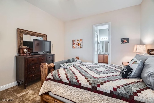 bedroom featuring ensuite bath, baseboards, and dark tile patterned flooring