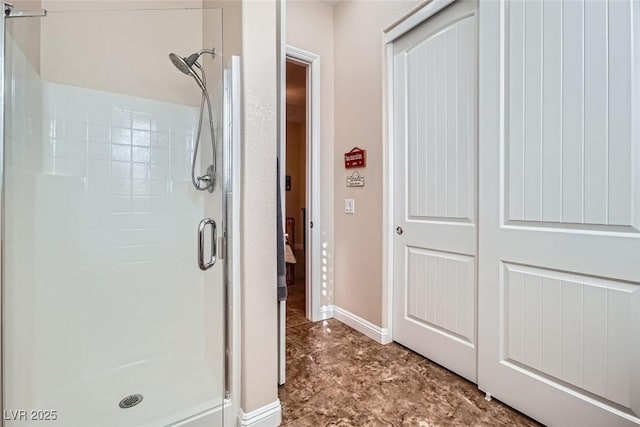 bathroom with a shower stall and baseboards