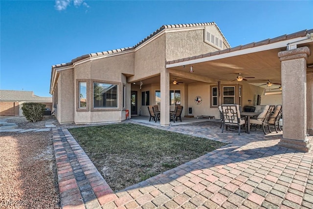 rear view of property with ceiling fan, outdoor dining area, a patio, and stucco siding