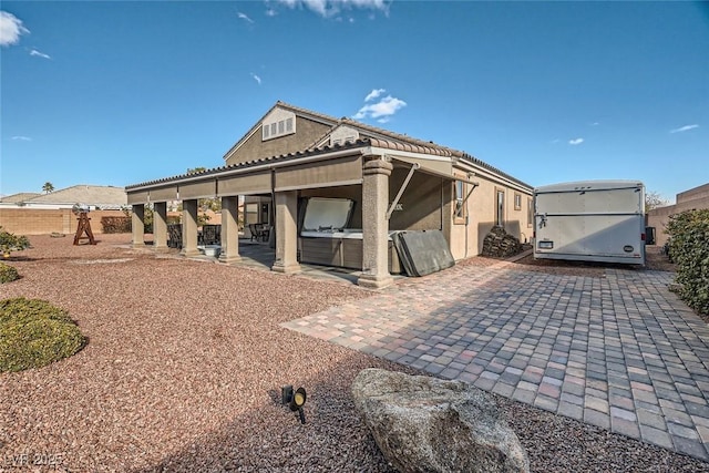 view of front of property with a patio, stucco siding, a playground, and a hot tub