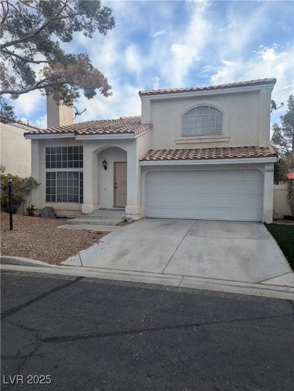 mediterranean / spanish house with a garage, a tiled roof, driveway, and stucco siding