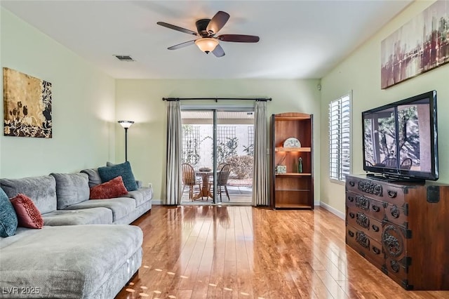 living area featuring plenty of natural light, wood-type flooring, visible vents, and ceiling fan