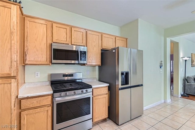 kitchen featuring light tile patterned floors, light brown cabinets, stainless steel appliances, and light countertops