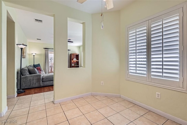 spare room featuring ceiling fan, light tile patterned flooring, visible vents, and baseboards