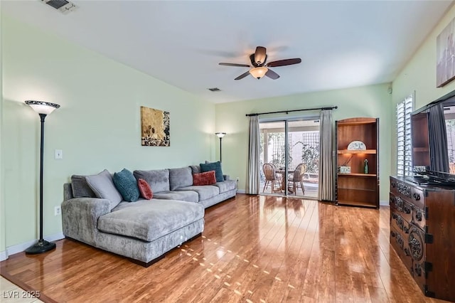 living area with baseboards, ceiling fan, visible vents, and wood finished floors