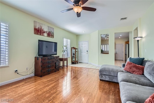 living room featuring light wood-style flooring, visible vents, ceiling fan, and baseboards