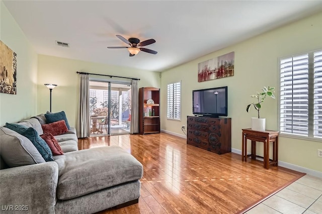 living area featuring light wood-style floors, visible vents, baseboards, and a ceiling fan