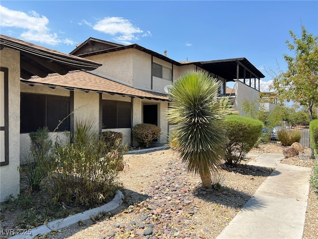 view of side of home featuring roof with shingles and stucco siding