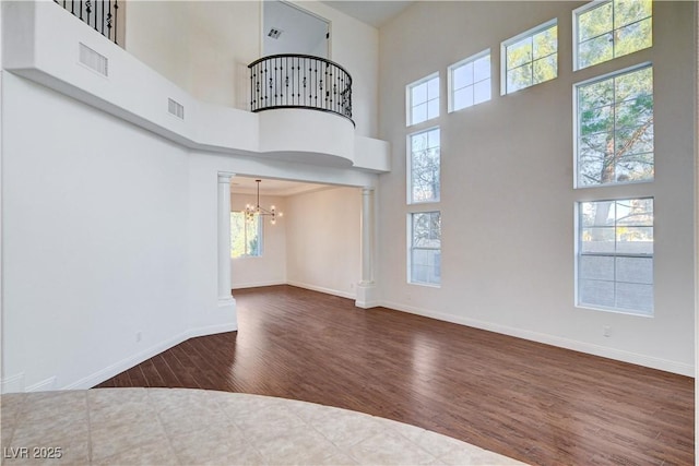 unfurnished living room featuring ornate columns, baseboards, visible vents, and wood finished floors