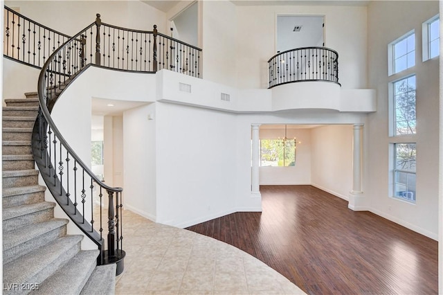 foyer entrance with visible vents, decorative columns, baseboards, and wood finished floors