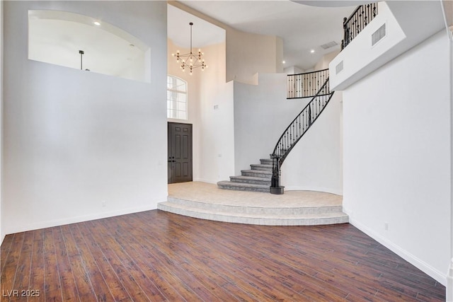 interior space featuring visible vents, stairway, a high ceiling, and hardwood / wood-style flooring