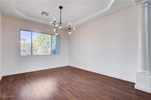 empty room with baseboards, visible vents, a tray ceiling, and dark wood-type flooring