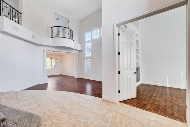 foyer entrance featuring a chandelier, visible vents, a high ceiling, and wood finished floors