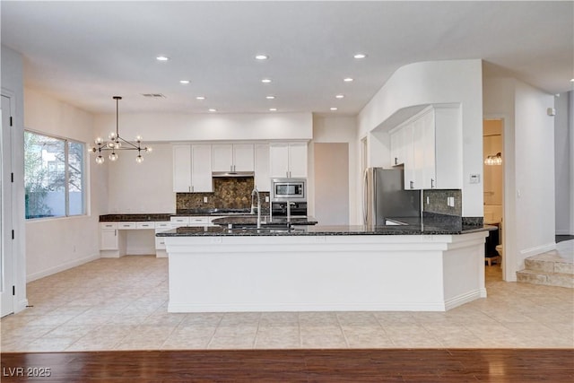 kitchen featuring a peninsula, white cabinetry, appliances with stainless steel finishes, and dark stone countertops