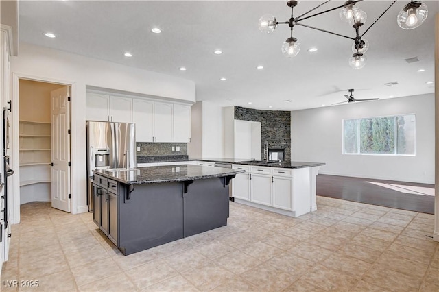 kitchen with open floor plan, white cabinets, a sink, a peninsula, and stainless steel fridge with ice dispenser