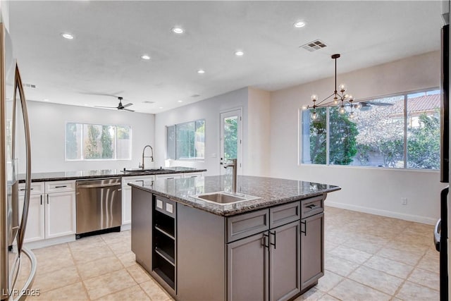 kitchen with an island with sink, visible vents, stainless steel appliances, and a sink