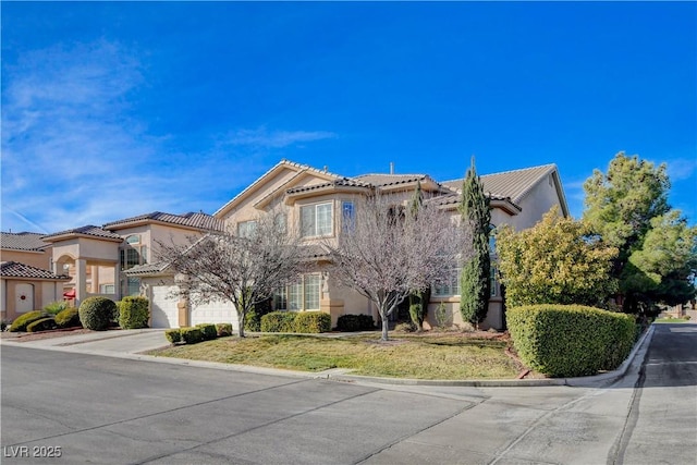 view of front of property featuring stucco siding, concrete driveway, a front yard, a garage, and a tiled roof