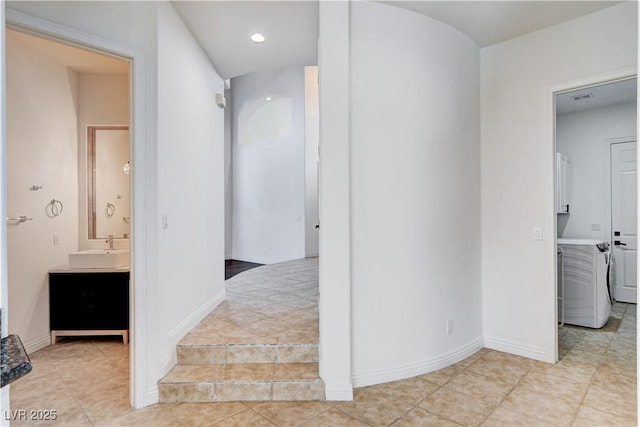 hall with visible vents, a sink, and baseboards