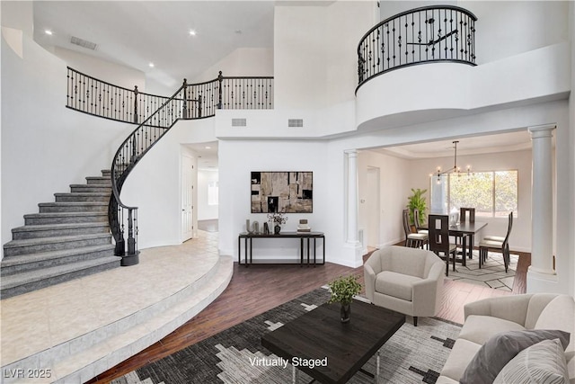 living area featuring an inviting chandelier, wood finished floors, visible vents, and ornate columns