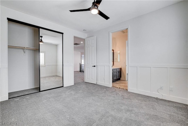 unfurnished bedroom featuring carpet floors, a closet, a wainscoted wall, and a ceiling fan