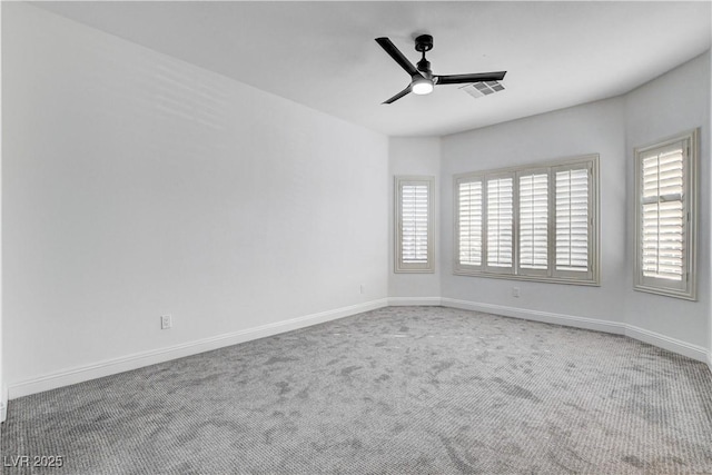 carpeted empty room with baseboards, visible vents, and a ceiling fan