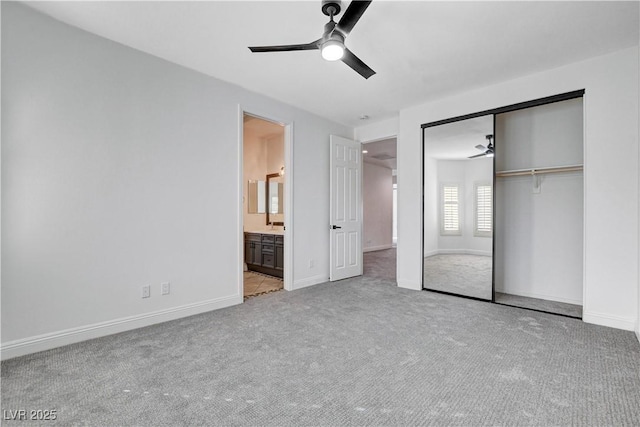 unfurnished bedroom with a closet, light carpet, baseboards, and ensuite bathroom