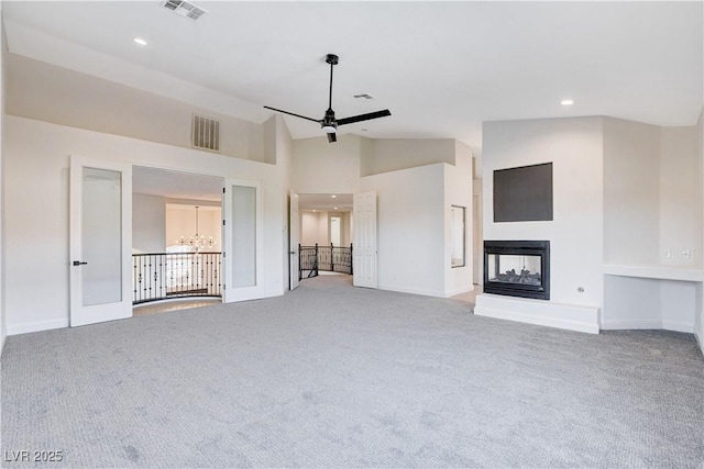 unfurnished living room with carpet, visible vents, ceiling fan, and a multi sided fireplace