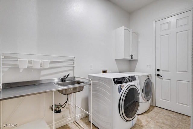 laundry area with washing machine and dryer, cabinet space, a sink, and baseboards