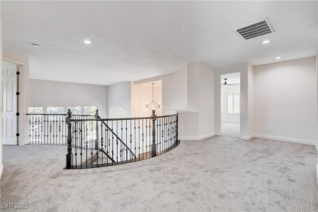 carpeted empty room with baseboards, plenty of natural light, visible vents, and an inviting chandelier