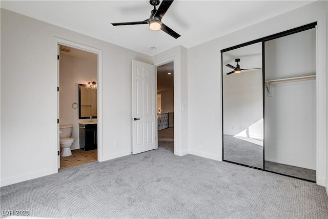 unfurnished bedroom with carpet floors, a closet, a ceiling fan, ensuite bath, and baseboards