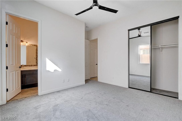 unfurnished bedroom featuring carpet floors, a closet, ensuite bathroom, a ceiling fan, and baseboards