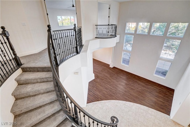 staircase with ceiling fan, wood finished floors, and baseboards