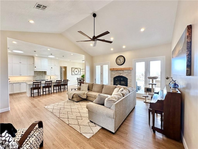 living room with baseboards, visible vents, light wood-type flooring, a fireplace, and recessed lighting