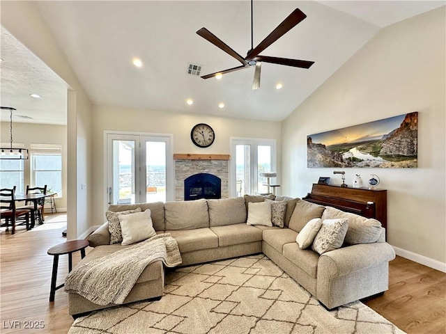 living area with light wood-type flooring, baseboards, visible vents, and a stone fireplace