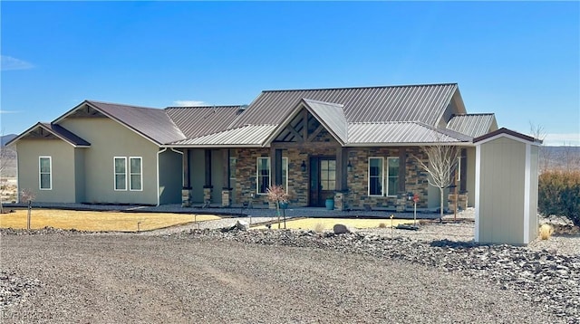 view of front of home featuring covered porch, stone siding, and metal roof