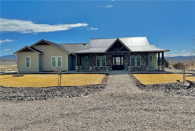 view of front of house with metal roof, stone siding, a front lawn, and stucco siding