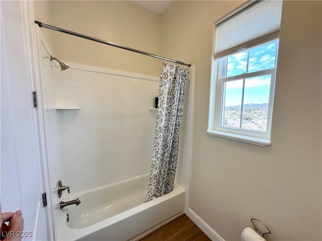 full bath featuring wood finished floors, shower / bath combo with shower curtain, and baseboards