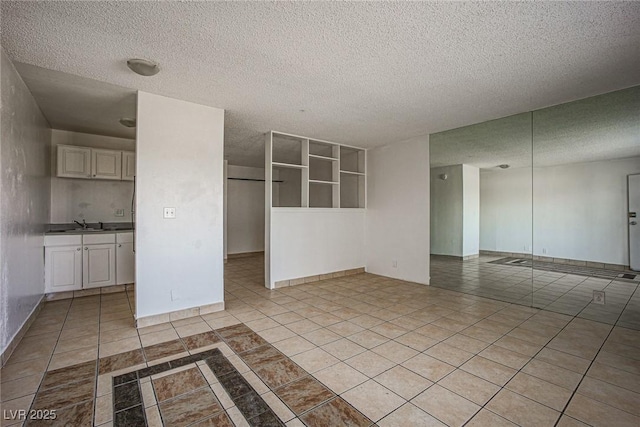 spare room featuring a textured ceiling, baseboards, and light tile patterned floors